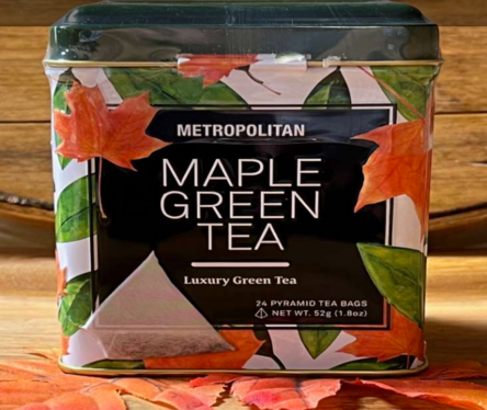 Maple Green Tea Tin of Metropolitan Maple Green Tea featuring 24 pyramid tea bags, placed on a wooden surface with autumn leaves, highlighting its luxury green tea blend.