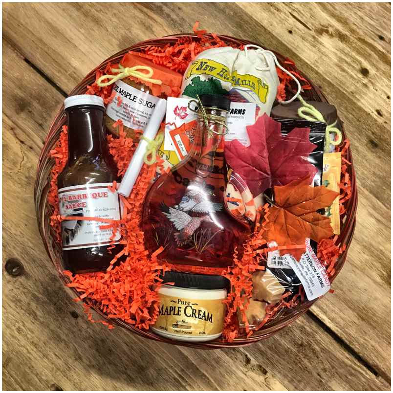 featuredproduct4 Gift basket filled with gourmet items including maple sugar, maple cream, barbecue sauce, and decorative autumn leaves, presented on a rustic wooden background. Perfect for fall celebrations or as a seasonal gift.